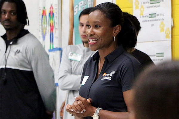 woman speaking and smiling to a group in a classroom or community setting
